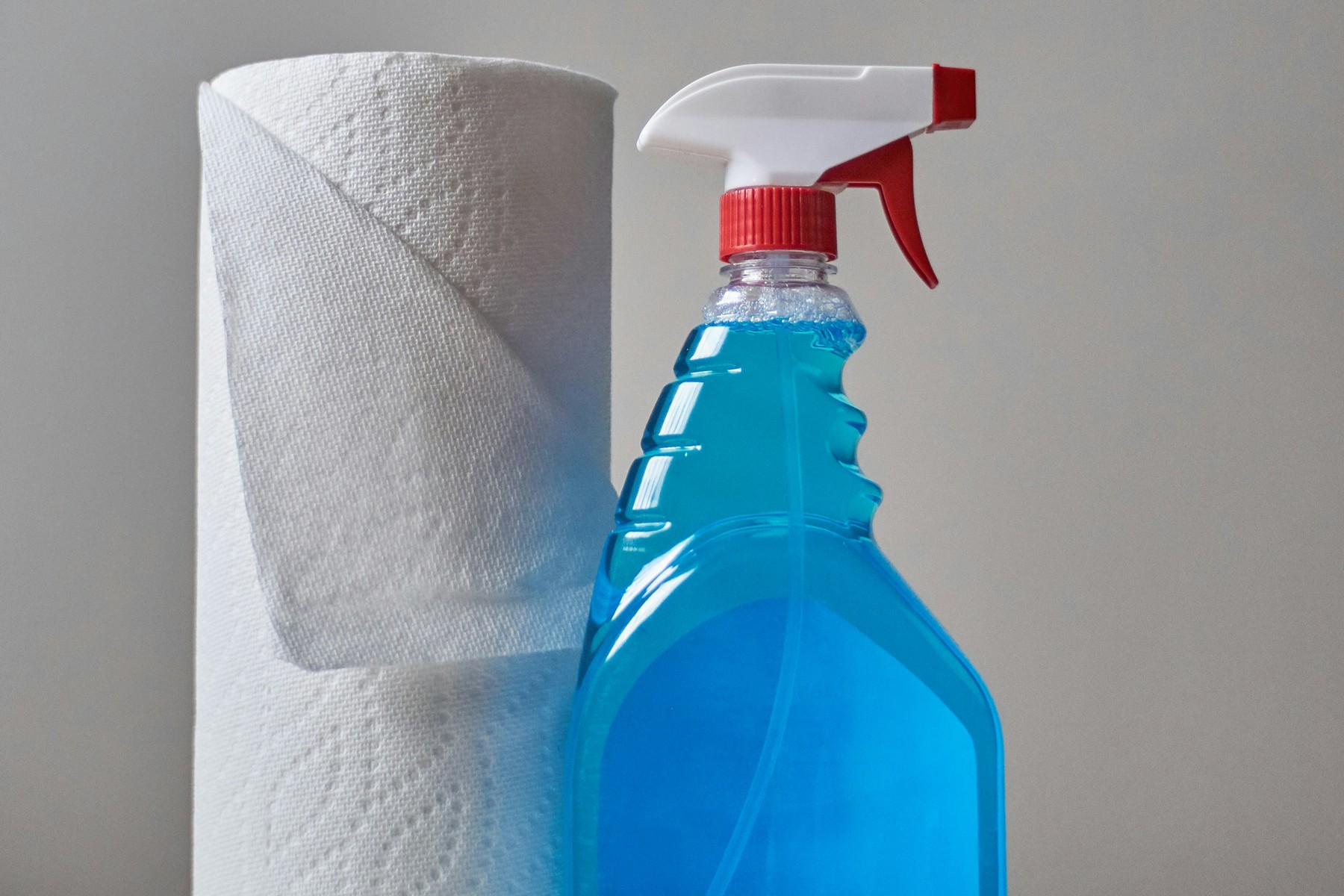 Sprühflasche mit Reiniger wird auf eine Fläche aufgetragen
